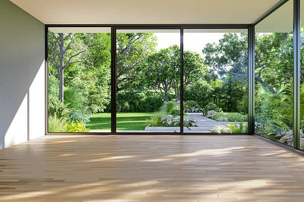 Empty living room with hardwood floors and floor-to-ceiling garden windows